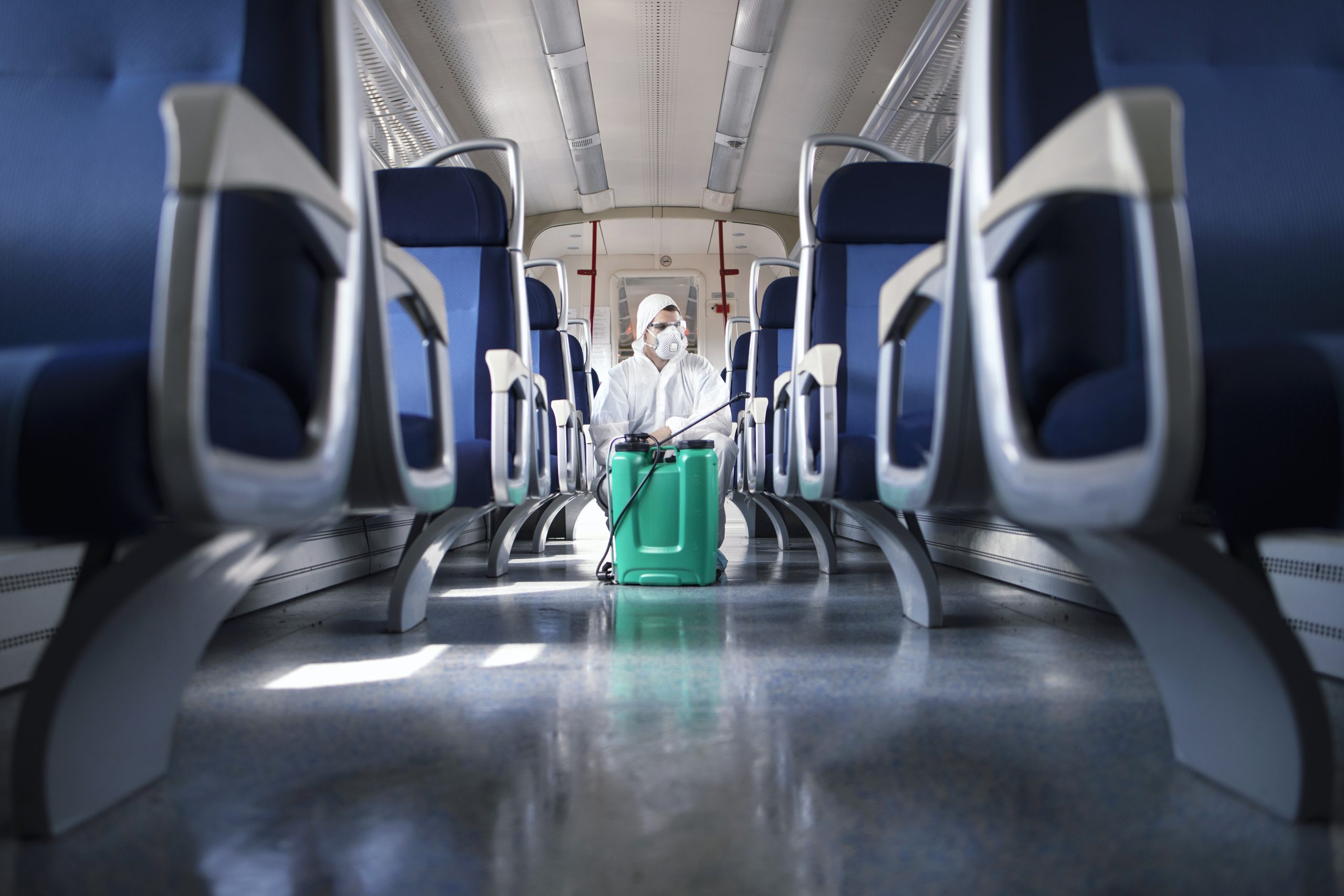 Man in white protection suit disinfecting and sanitizing subway train interior to stop spreading highly contagious corona virus.